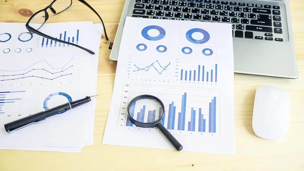 Analytical reports with graphs and a magnifying glass, highlighting digital marketing reporting insights.